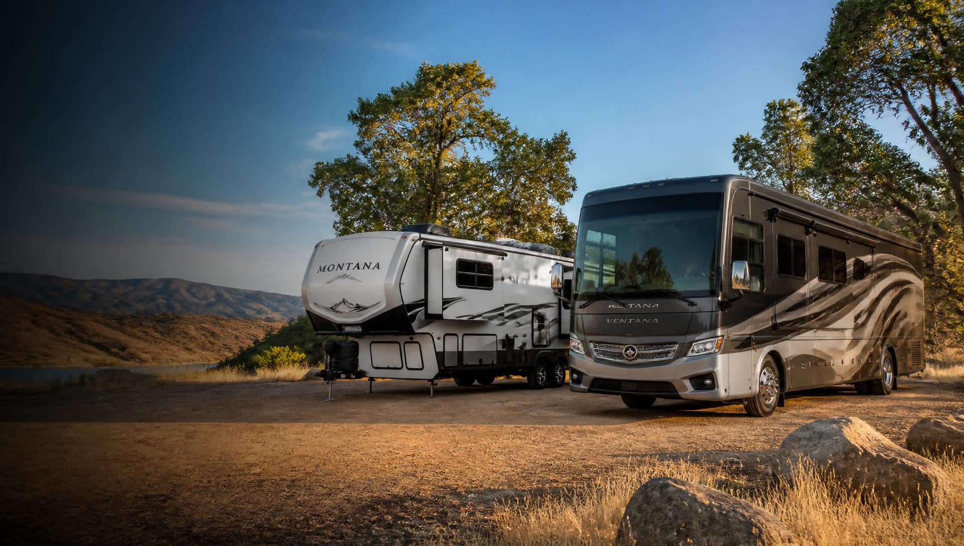 Class A motorhome and travel trailer parked in a California field at sunset